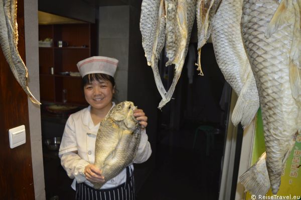 Köchin mit Fisch aus Qufu in China,  